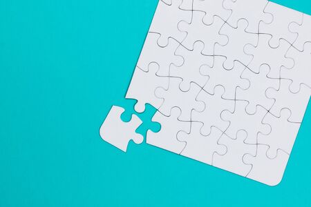 Close-up white jigsaw puzzle with a missing piece - blue backgroundの写真素材