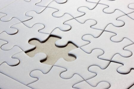 Close-up white jigsaw puzzle with a missing piece - full frame white backgroundの写真素材