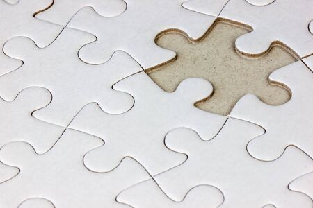 Close-up white jigsaw puzzle with a missing piece - full frame white backgroundの写真素材
