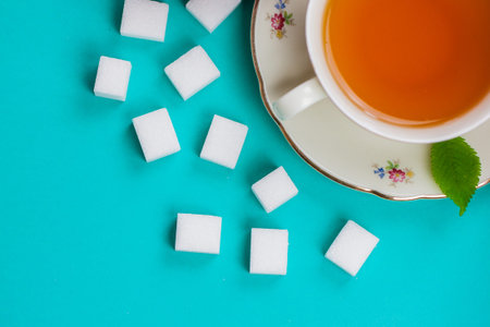 Traditional tea cup and saucer on a pastel blue background. Golden tea with honey. Flat lay, top view.の写真素材