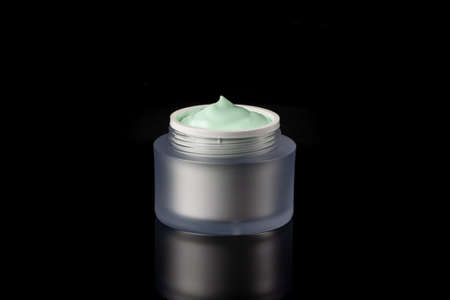 Glass jar of beauty face cream with cap. Isolated on black backgroundの写真素材