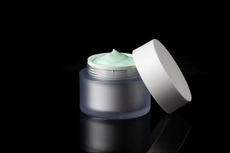 Glass jar of beauty face cream with cap. Isolated on black backgroundの写真素材