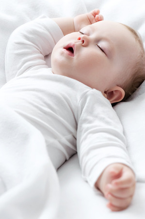 Carefree sleeping little baby on a bedの写真素材