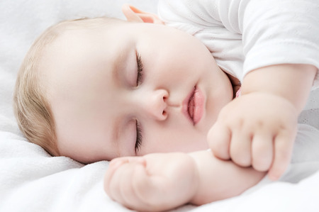 Carefree sleeping little baby on a bedの写真素材