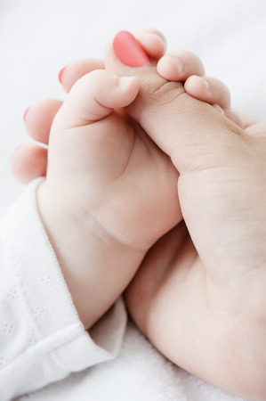 Hand of the child in a hand of mother on a pillowの写真素材