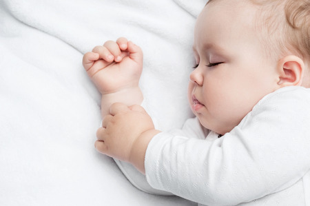 Carefree sleeping little baby on a bedの写真素材