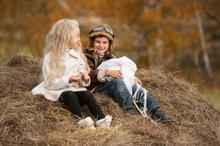 Boy with a girl sitting on a haystack with a parachute in the autumn sunny dayの写真素材