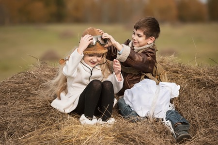 Boy with a girl sitting on a haystack with a parachute in the autumn sunny dayの写真素材