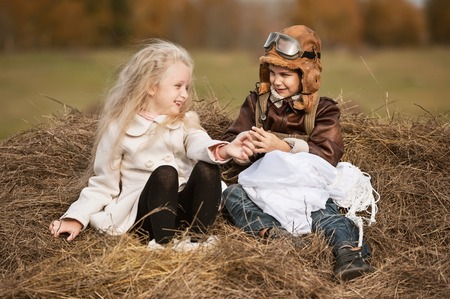 Boy with a girl sitting on a haystack with a parachute in the autumn sunny dayの写真素材