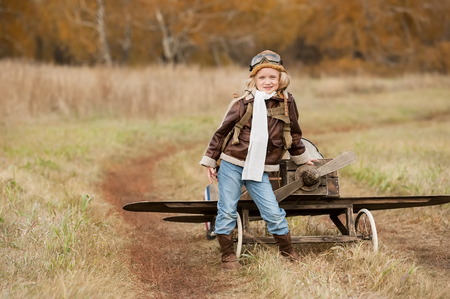 Young female pilot in a homemade airplane on a field road at sunny autumn dayの写真素材