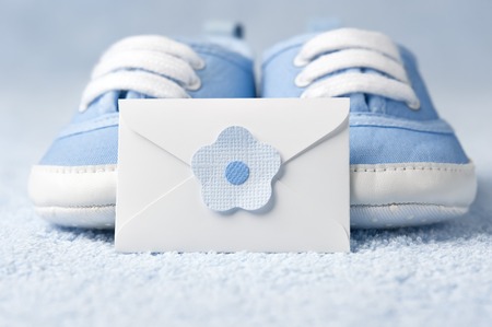 Little baby booties with an envelope on a blue backgroundの写真素材