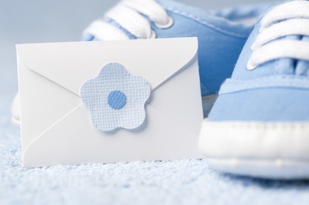 Little baby boots with an envelope on a blue backgroundの写真素材