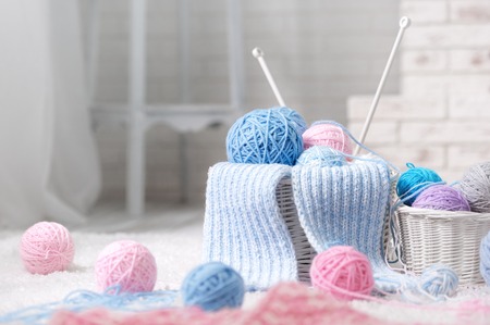 Wicker basket with a variety of balls of yarn on the carpet by the fireplace in the interiorの写真素材