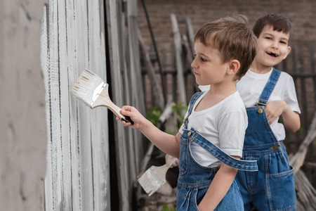 Boys-painters with brushes and paint at an old wall on a summer dayの写真素材