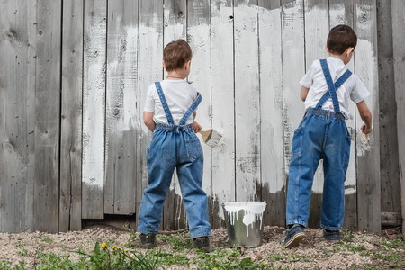 Boys-painters with brushes and paint at an old wall on a summer dayの写真素材