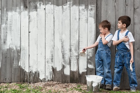 Boys-painters with brushes and paint at an old wall on a summer dayの写真素材