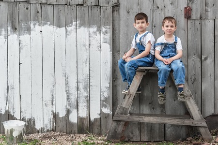 Boys-painters with brushes and paint at an old wall on a summer dayの写真素材