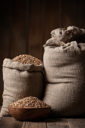 Grain of the wheat in bags on a wooden plank floorの写真素材