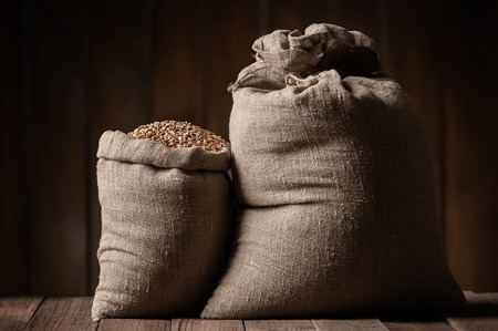 Grain of the wheat in bags on a wooden plank floorの写真素材