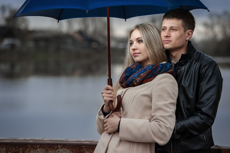 Guy and the girl under an umbrella on a bridge on a cloudy rainy dayの写真素材