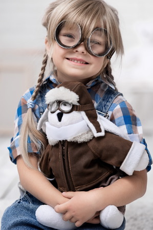 Portrait of a little girl with a toy bunny-pilot in the interiorの写真素材