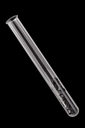 Slices of coal in a test tube on a black backgroundの写真素材