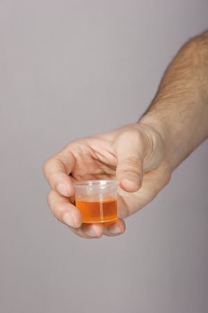 Syrup in a mensural glass in a hand on a grey backgroundの写真素材
