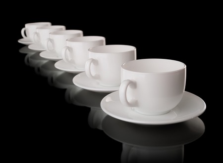 Heap of the white cups and saucers, isolated on blackの写真素材