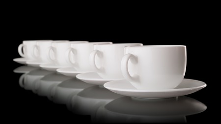 Heap of the white cups and saucers, isolated on blackの写真素材