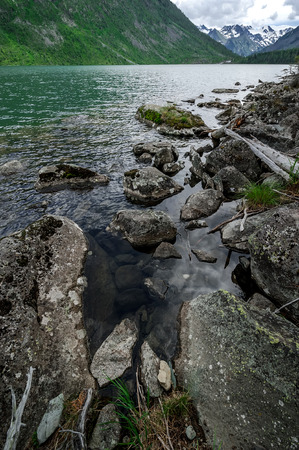 Stony coast of mountain lake summer cloudy dayの写真素材