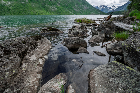 Stony coast of mountain lake summer cloudy dayの写真素材