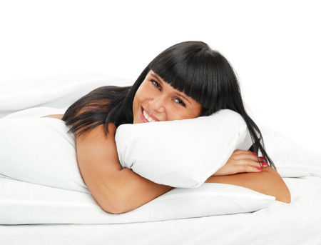 Young girl - brunette on white bed in a bedの写真素材