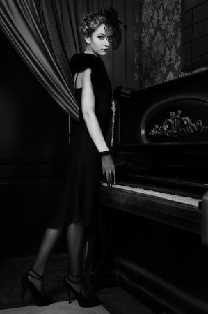 Portrait of a young girl in a retro style in the interior of the pianoの写真素材