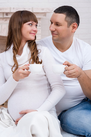 Young couple waiting for a baby drink tea by the fireの写真素材