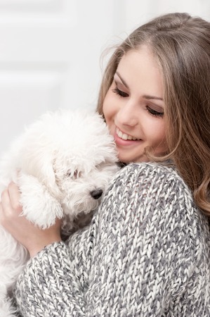 Portrait of a young girl with a little white dog in her armsの写真素材