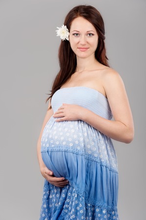 Portrait of the young pregnant girl on a gray backgroundの写真素材