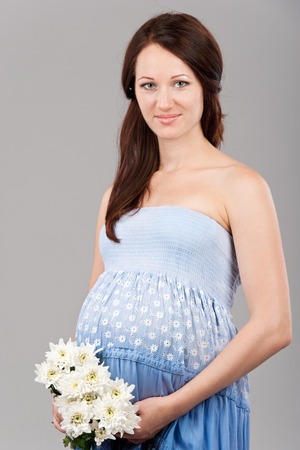 Portrait of the young pregnant girl on a gray の写真素材