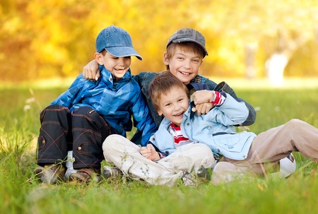 Three boys with a football merry in a warm autumn dayの写真素材