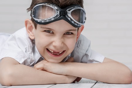 Portrait of a happy little boy with glasses in the pilot's room on the floorの写真素材