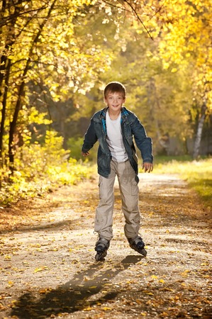 Young boy on roller skates on autumn maple alleyの写真素材