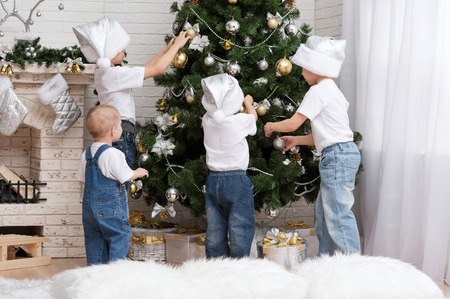 Four young children decorate the Christmas tree with beautiful toysの写真素材
