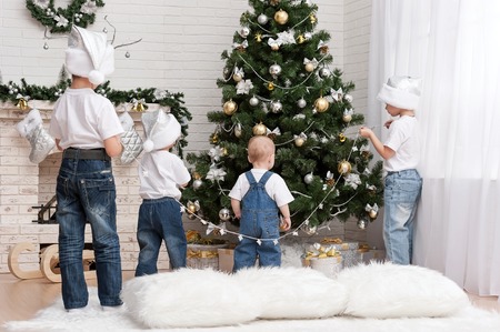 Four young children decorate the Christmas tree with beautiful toysの写真素材