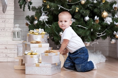 Portrait of a young boy on a sled with a gift of the Christmas treeの写真素材