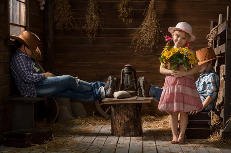 Three young children playing cowboys in the barnの写真素材