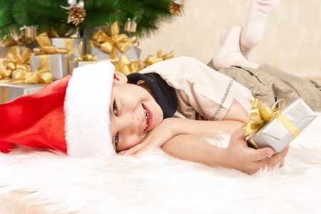 Happy little boy with a gift under the treeの写真素材