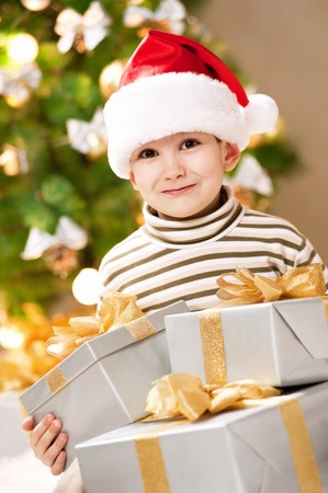 Happy little boy with a gift under the treeの写真素材