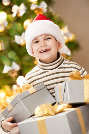 Happy little boy with a gift under the treeの写真素材