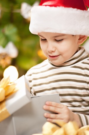 Happy little boy with a gift under the treeの写真素材