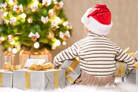 Happy little boy with a gift under the treeの写真素材