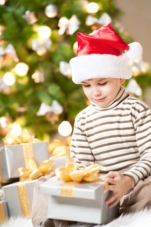 Happy little boy with a gift under the treeの写真素材